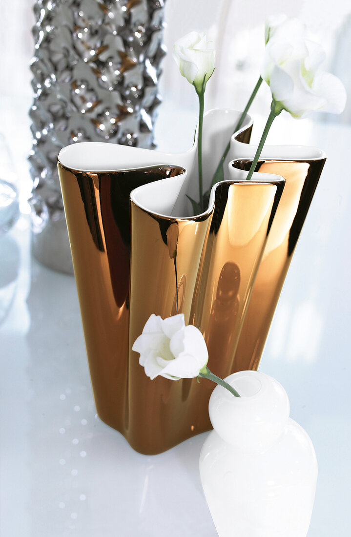 Close-up of copper flower vase with white swinging flowers