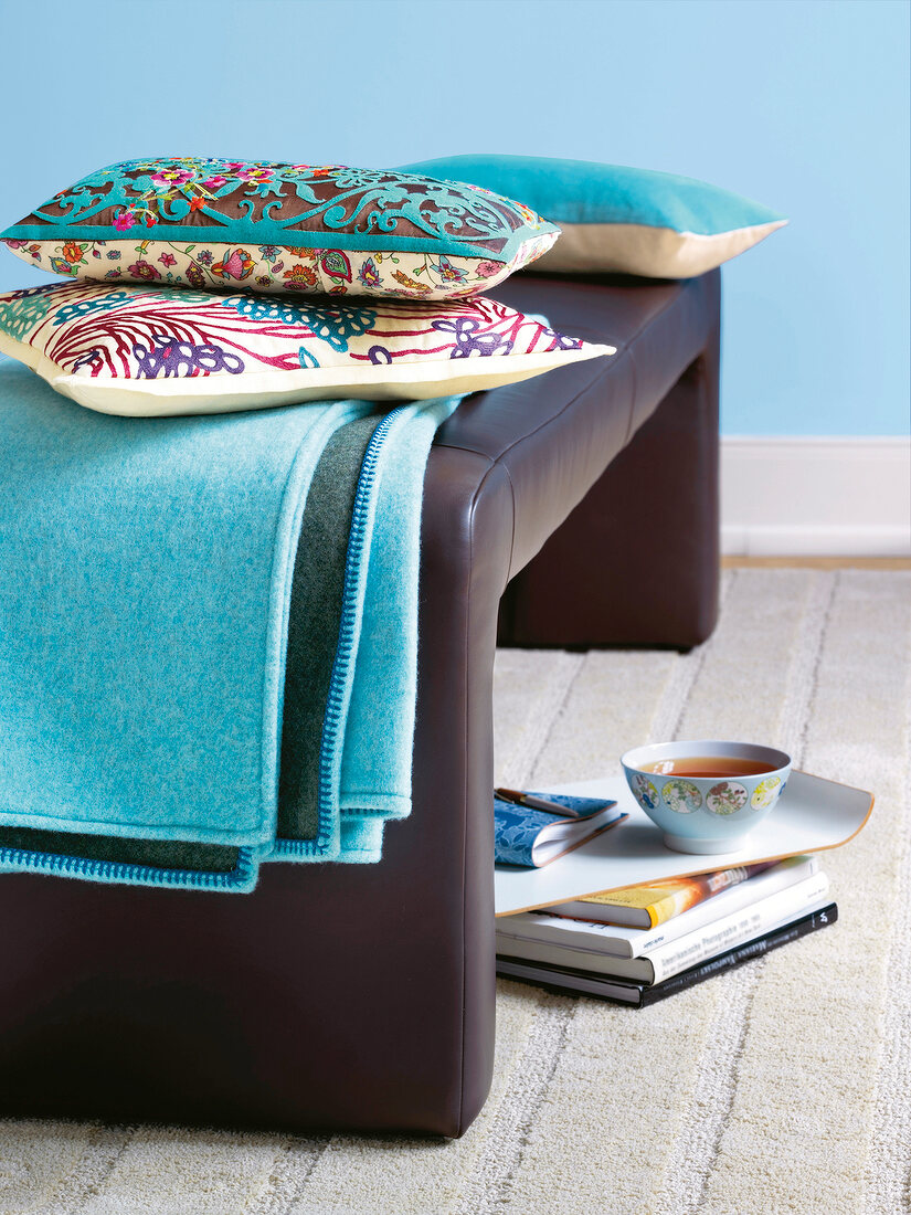 Brown leather bench with blue and beige ornamental print cushions