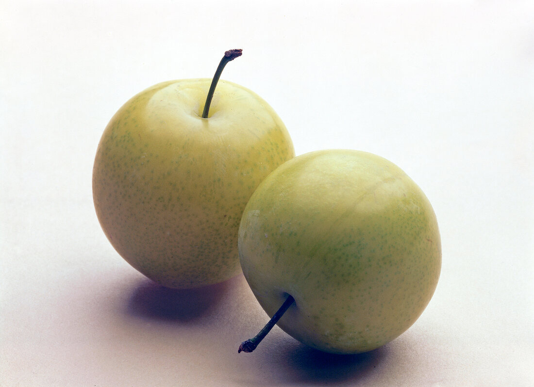 Two yellow mirabelle on white background