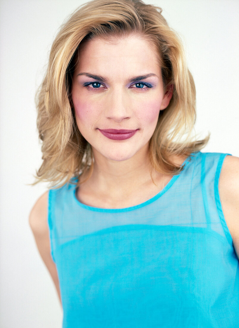 Confident looking blue eyed blonde woman wearing bright eyes make-up and pink lipstick