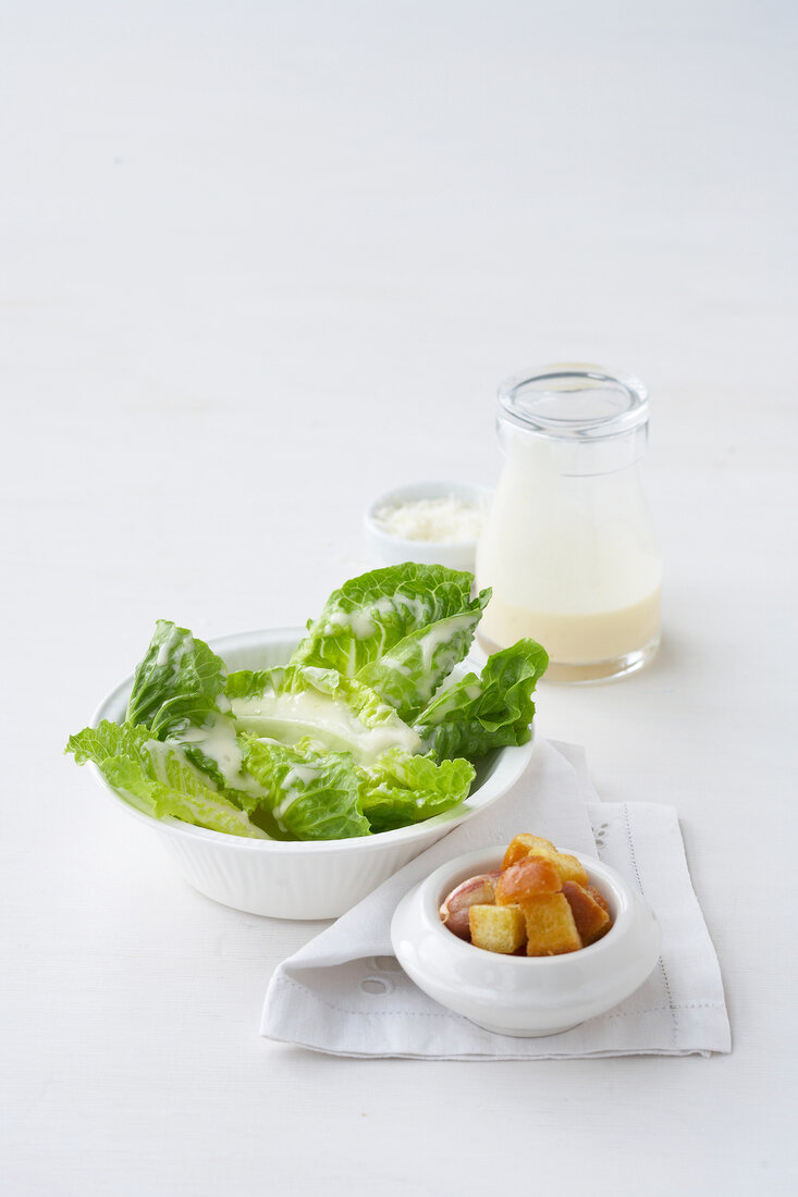 Caesar Salad neben Dressing Baguettewürfel