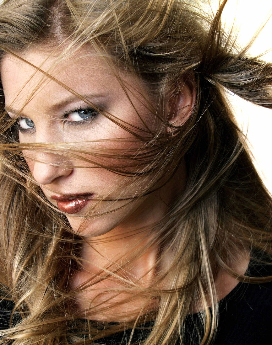 Close-up of blue eyed young woman with windswept hair looking sceptically