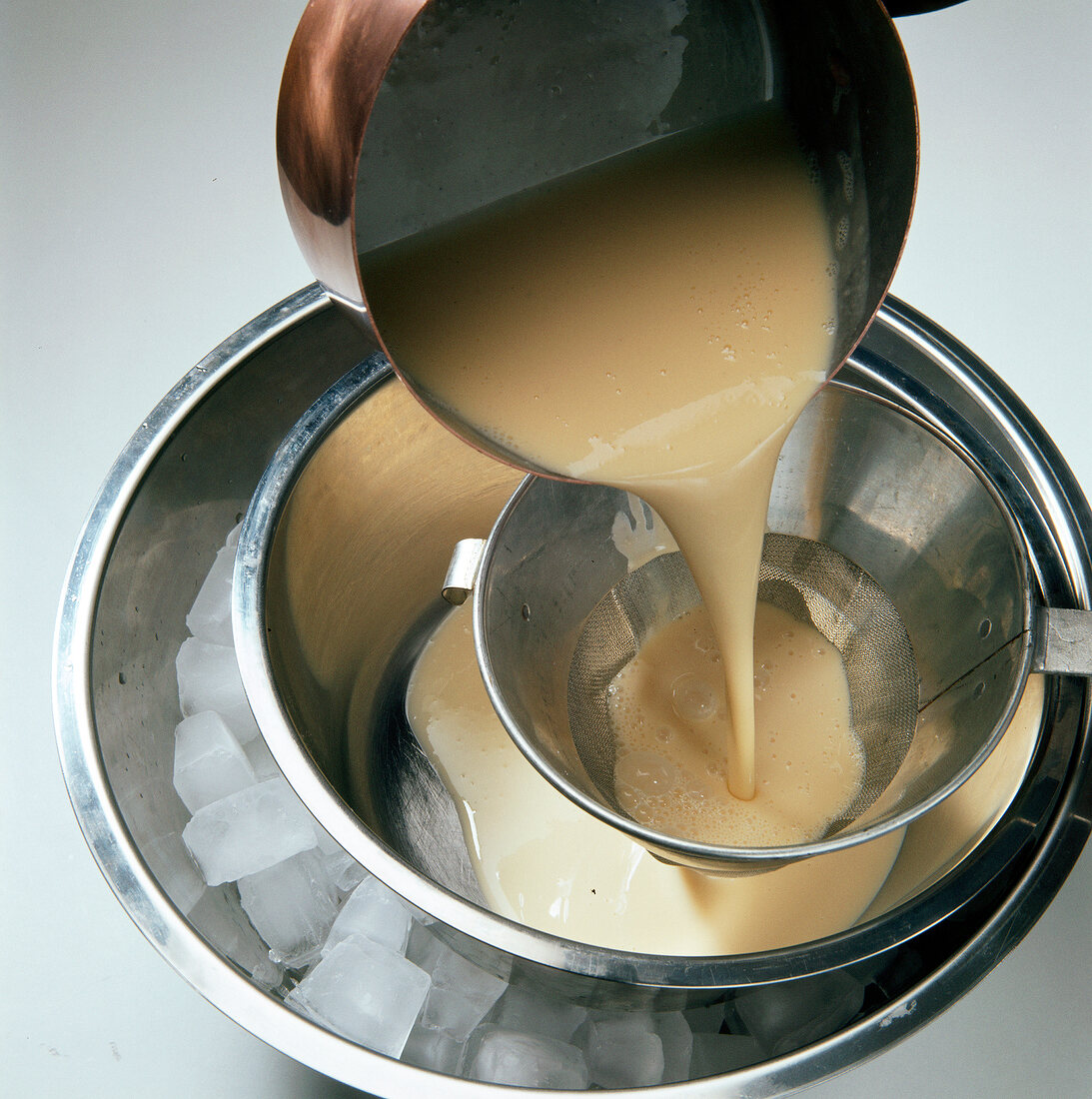 Pouring cream through sieve in pot for preparation of dessert, step 2