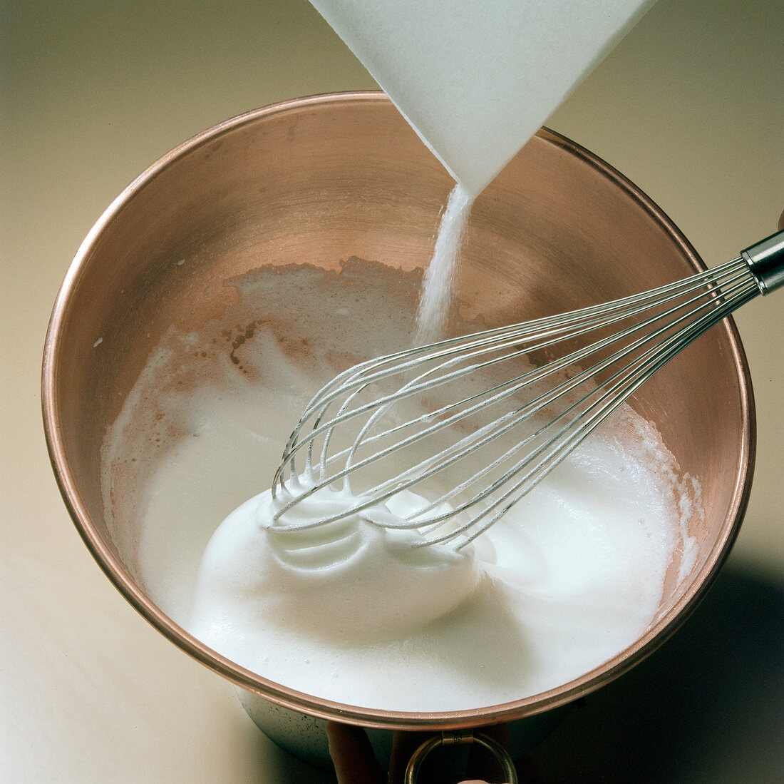 Sugar being added in cream for preparation of meringue, step 3
