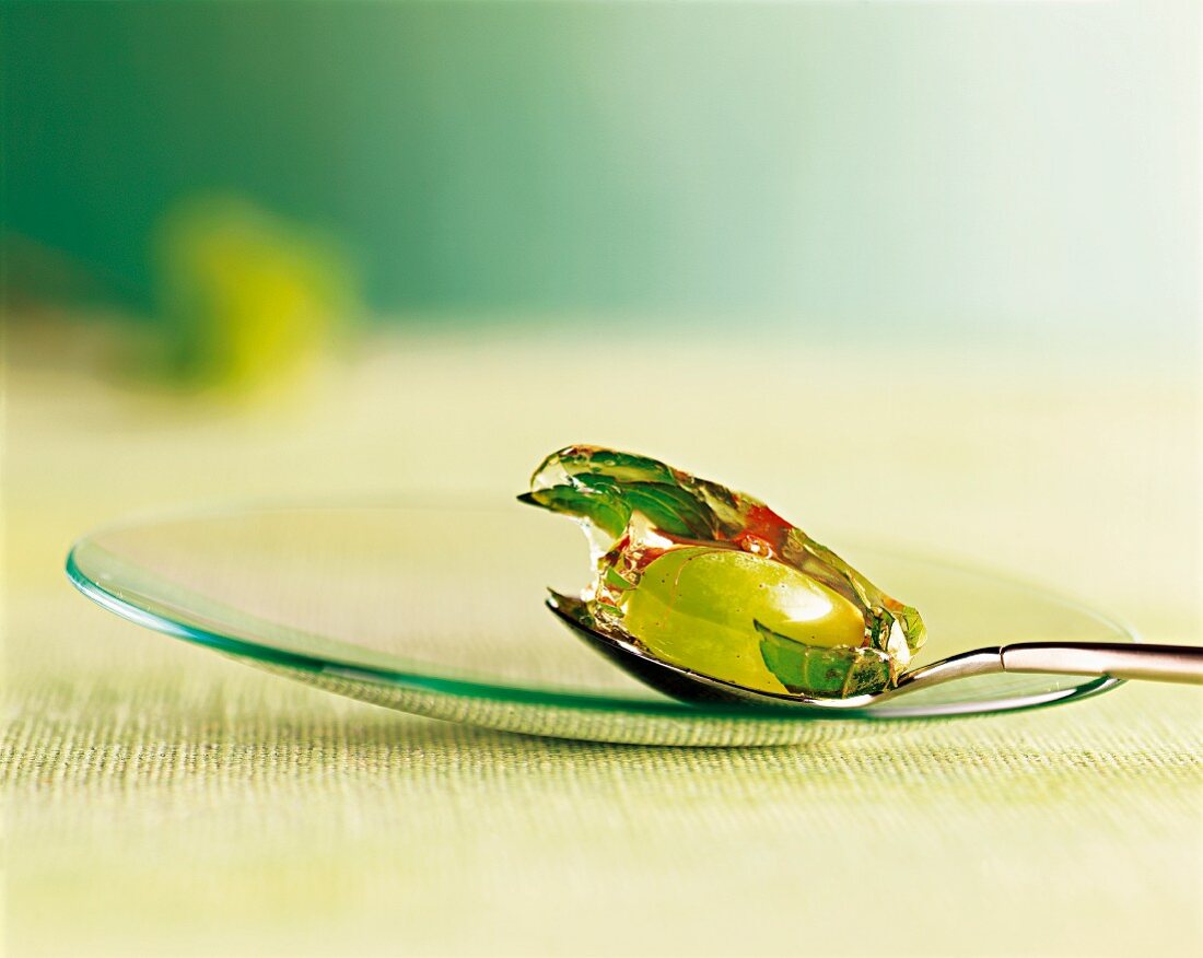 Grape and mint in jelly on spoon on a glass plate