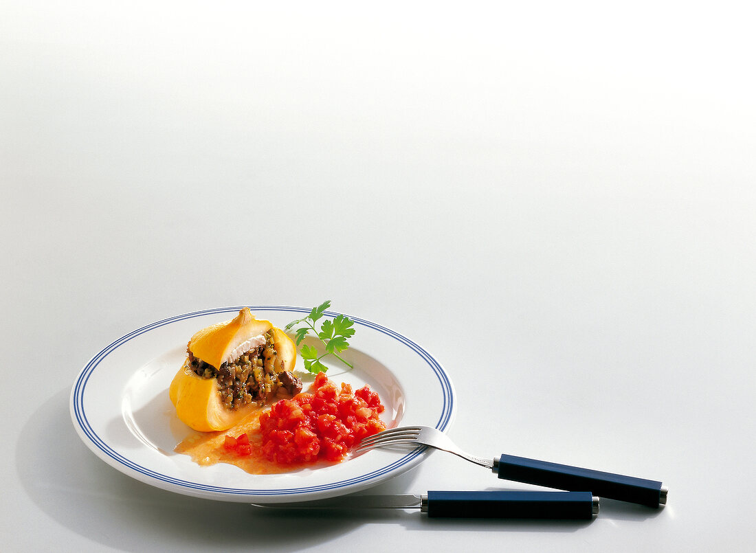 Patty pan filled with partridge and tomato sauce on plate with fork and knife