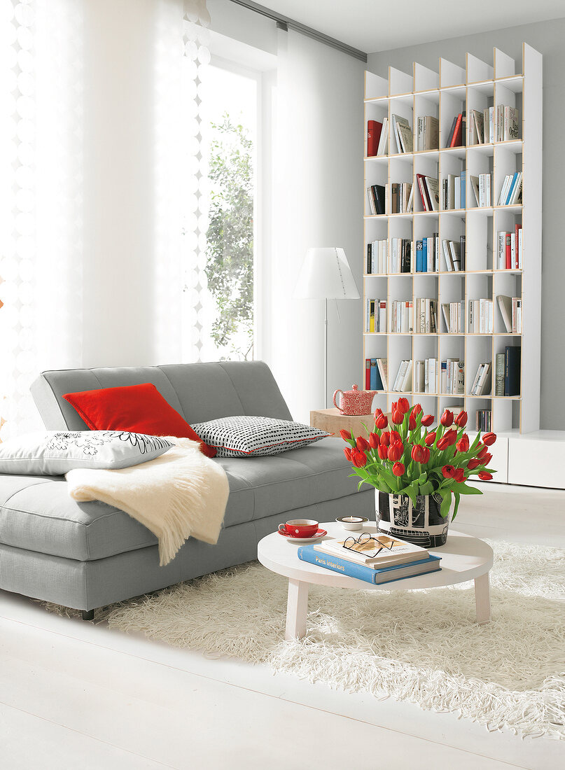 Living room in white with grey sofa and bookshelf