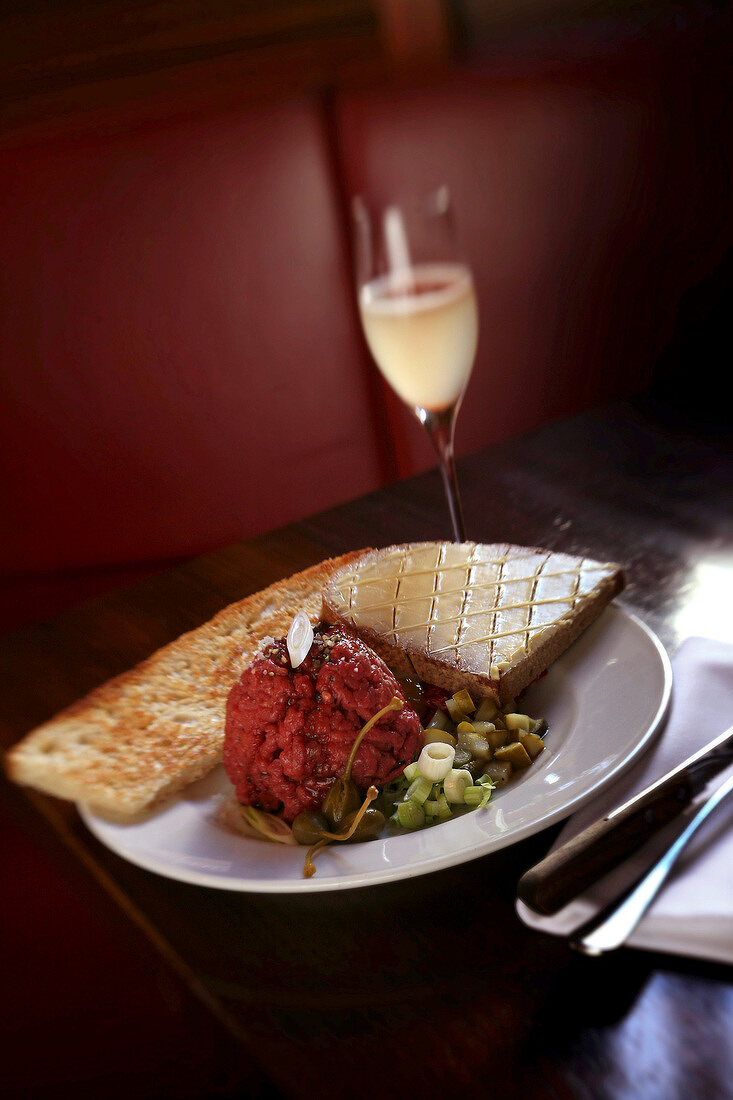 Steak tartare on plate served with pisco sour cocktail