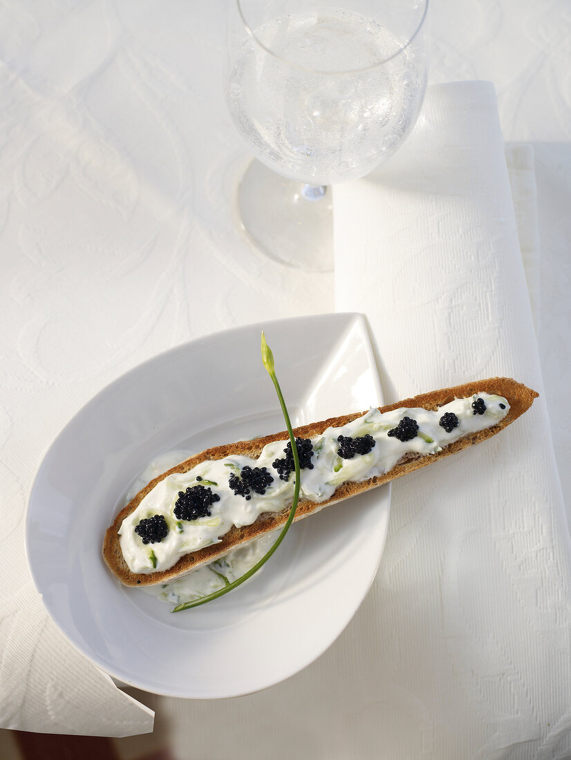Ciabatta with sour cream, cucumber and seaweed caviar on serving dish