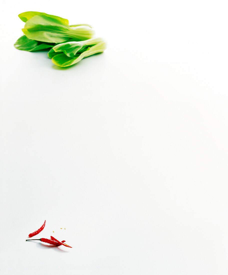 Pak choi leaves and chilies on white background