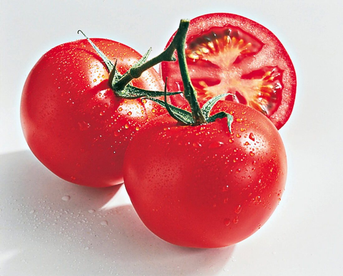 Close-up of whole and halved wet tomatoes
