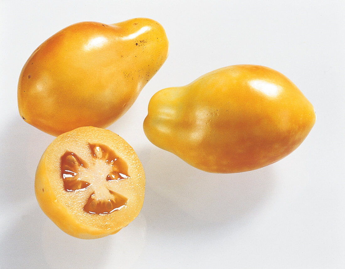 Close-up of whole and halved yellow pear on white background