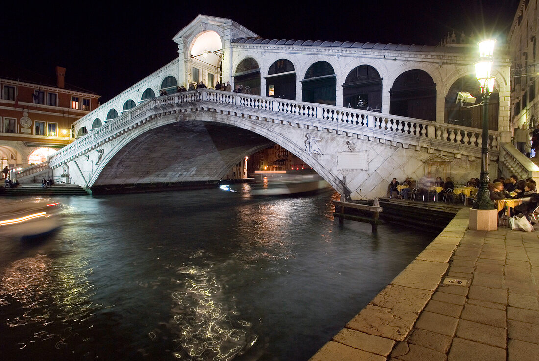 View of illuminated Rialto Bridge with arcades, Venice, Italy