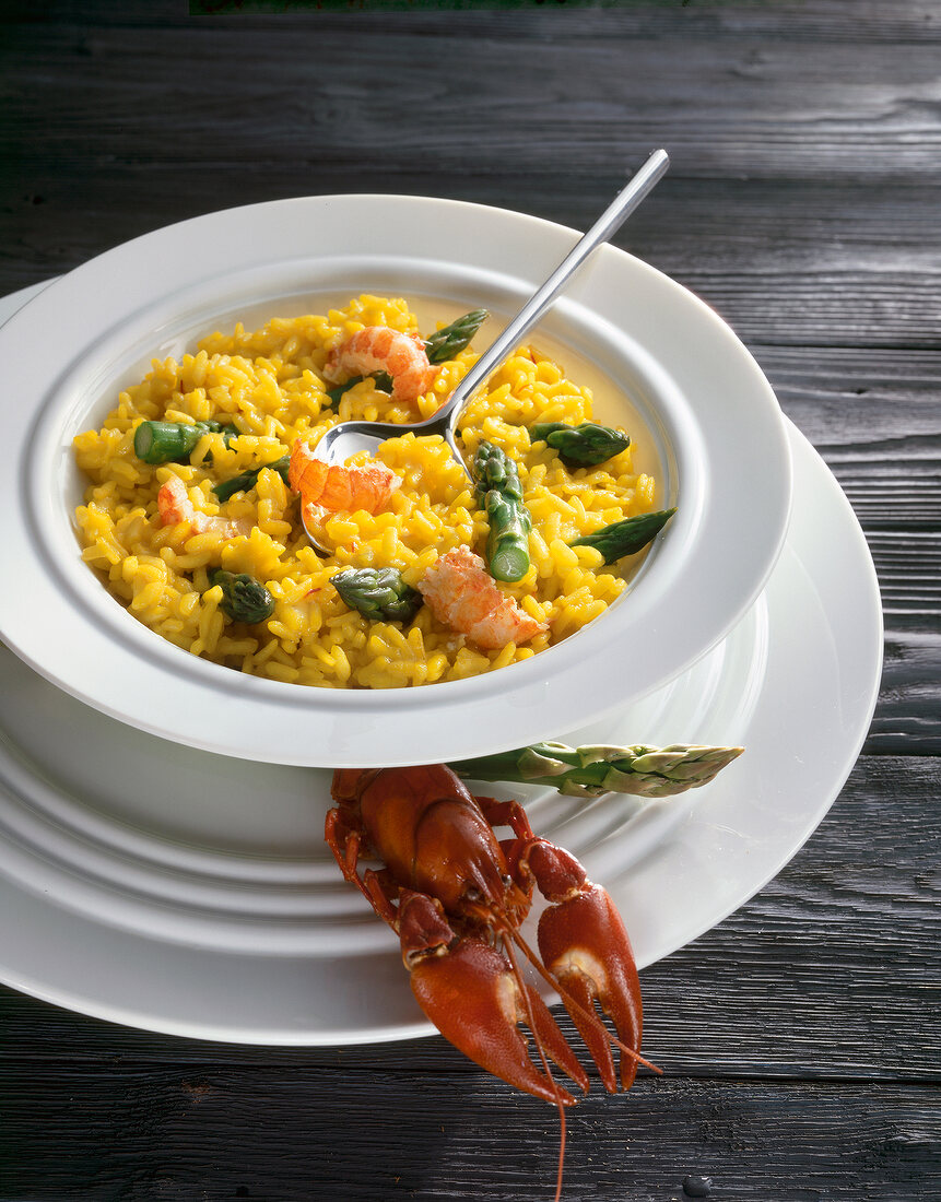 Saffron risotto with asparagus on plate beside crayfish