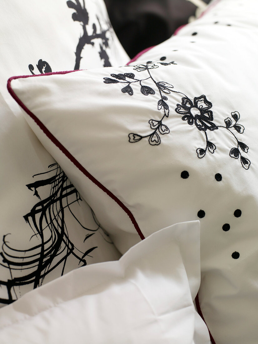 Close-up of white cushion with embroidered floral motif in black
