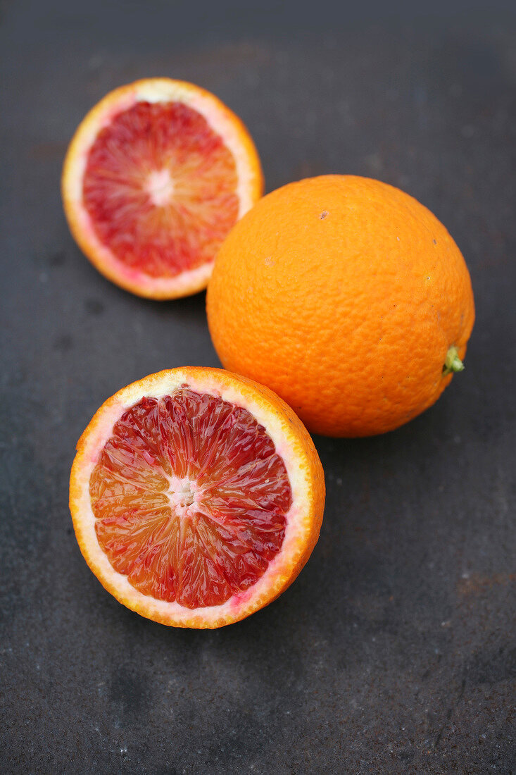 Close-up of whole and halved blood oranges