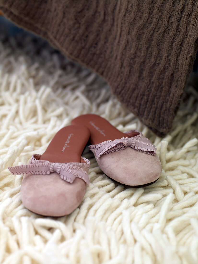 Close-up of mules in pink with bow on wool carpet