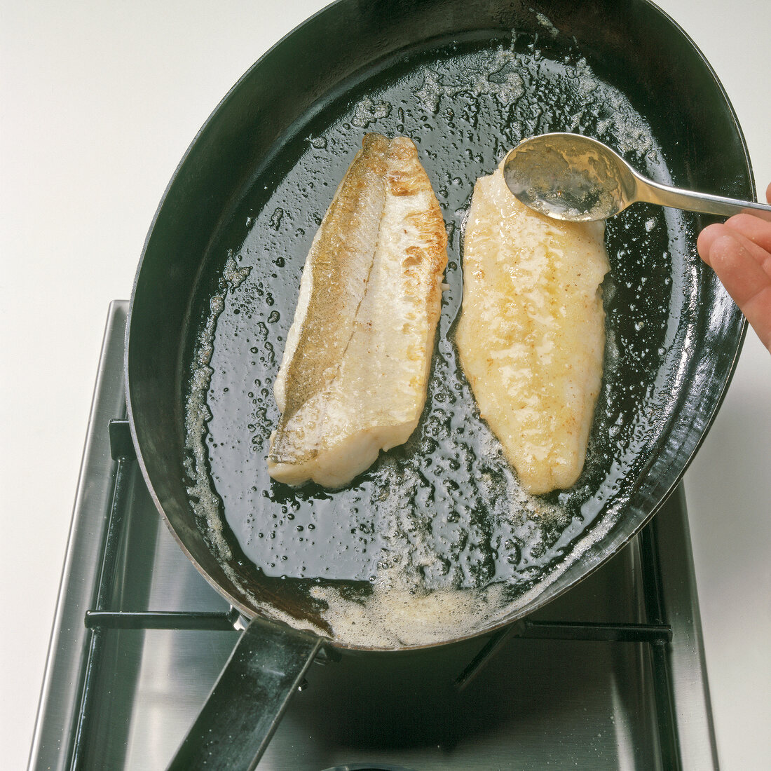 Merlan fillets being fried with butter in pan, step 3