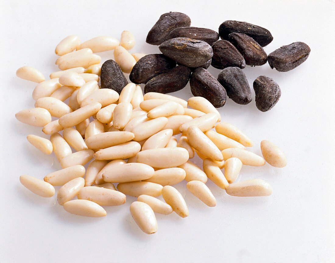Shelled and unshelled pine nuts on white background