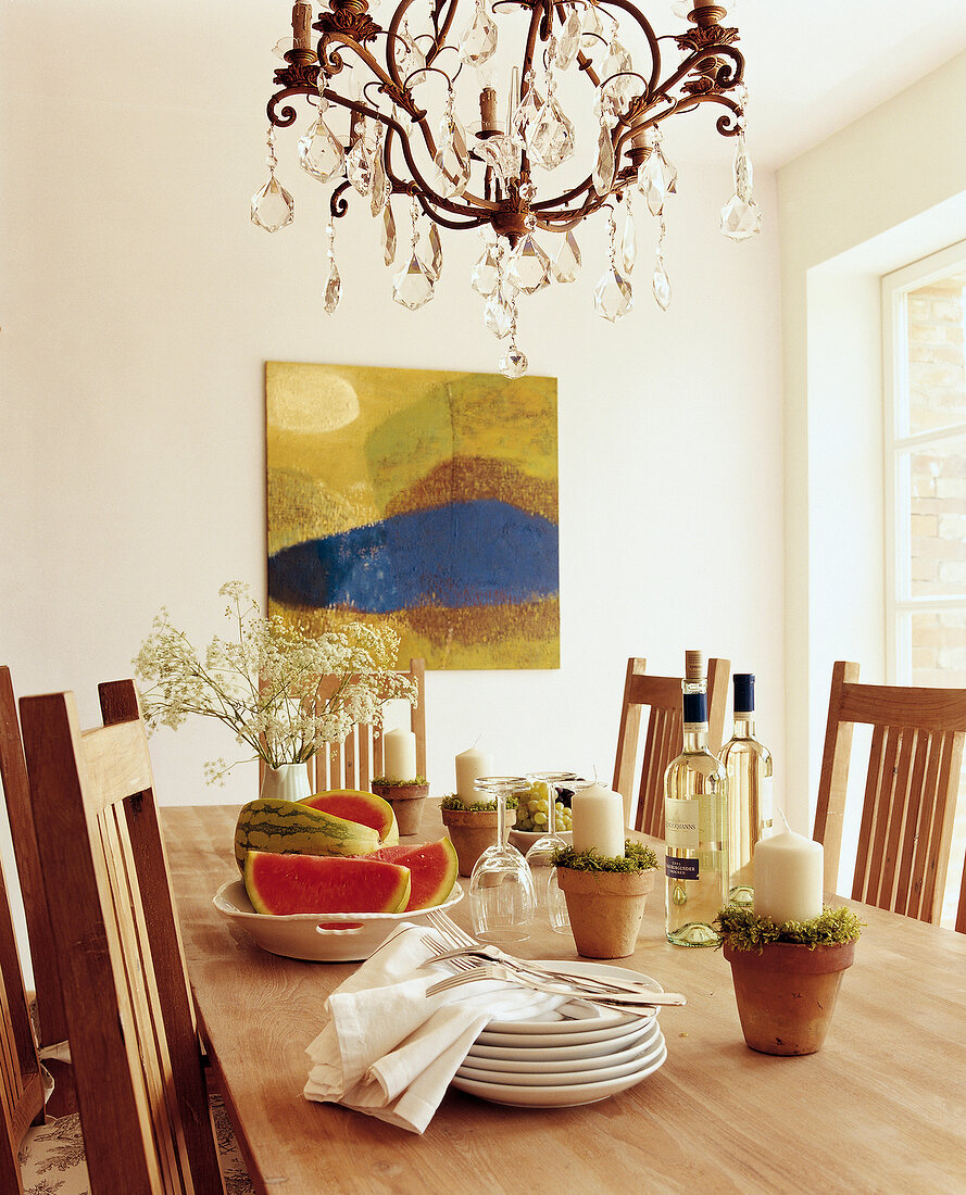 Dining table with flower pots, cutlery and chandelier on top