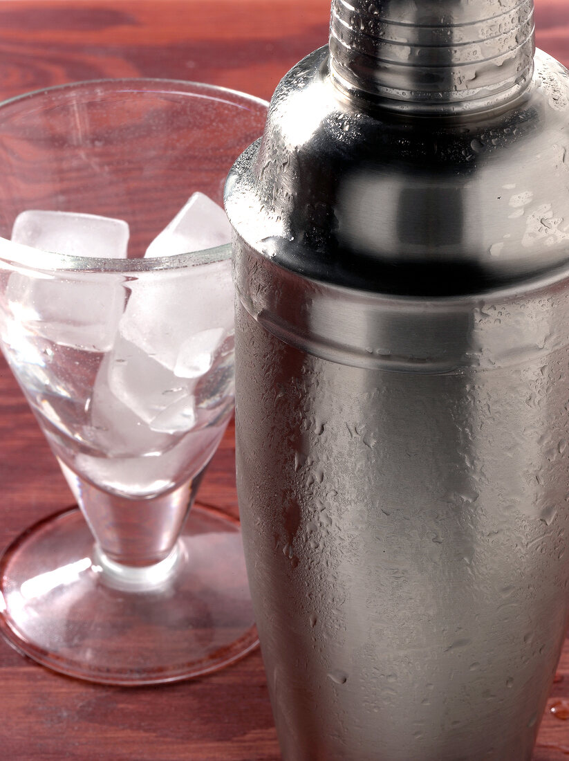 Close-up of cocktail shaker besides glass with ice cubes