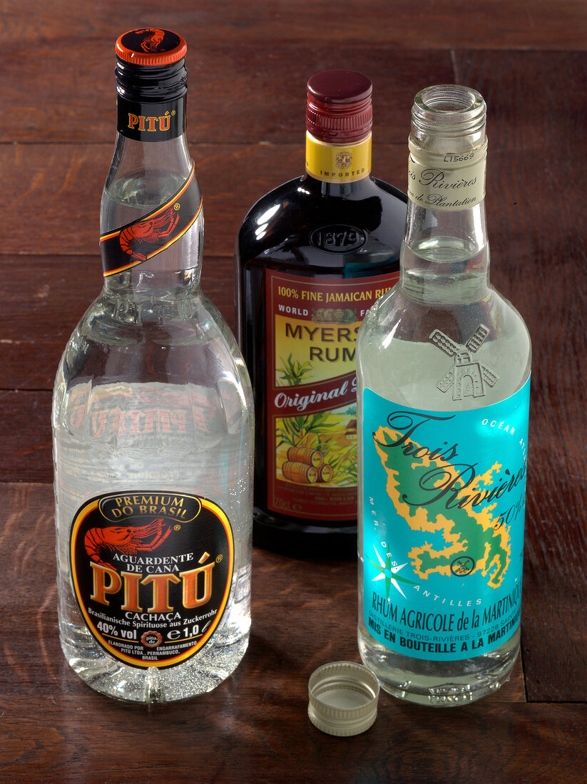 Three bottles of cachaca and rum on wooden table