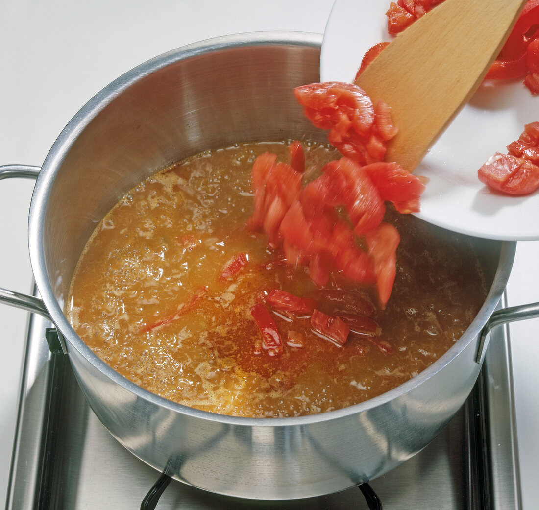 Tomato and pepper strips being added to mixture in pot, step 5