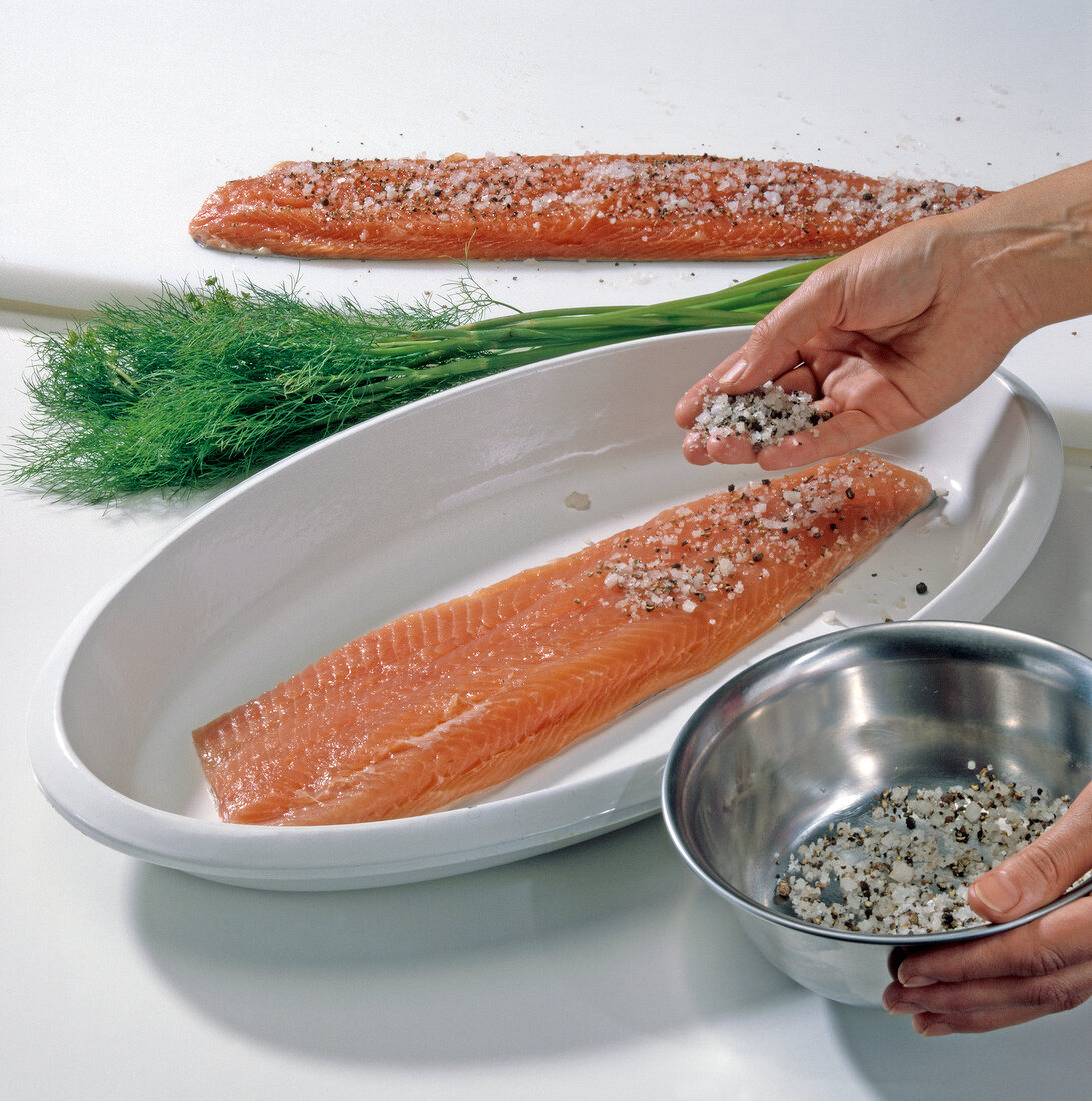 Salt, spice and pepper mixture being sprinkled on salmon trout, step 1