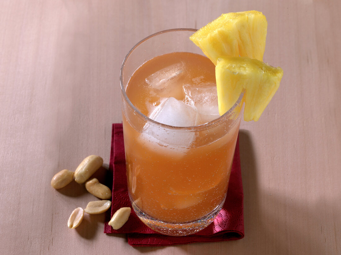 The juxtaposition cocktail in glass with pineapple cubes on rim