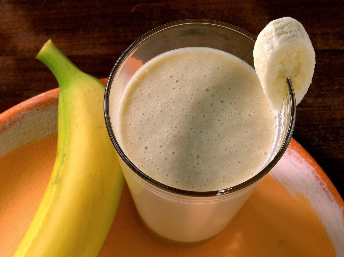 Cocobanana juice in glass with banana piece on rim