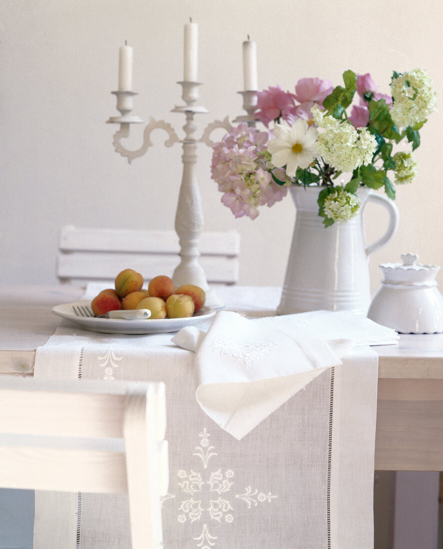 Table decorated with flowers, candle stand and fruits in plate