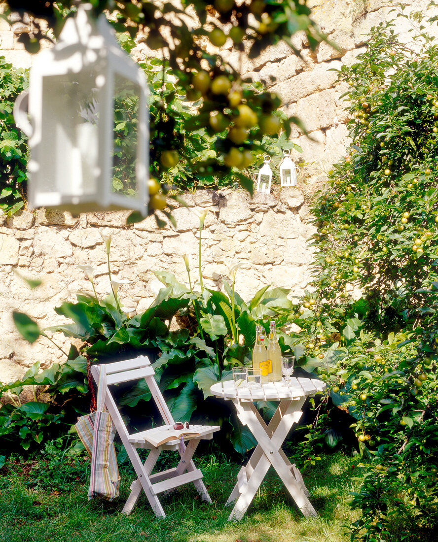White folding chair and table with drinks in the garden