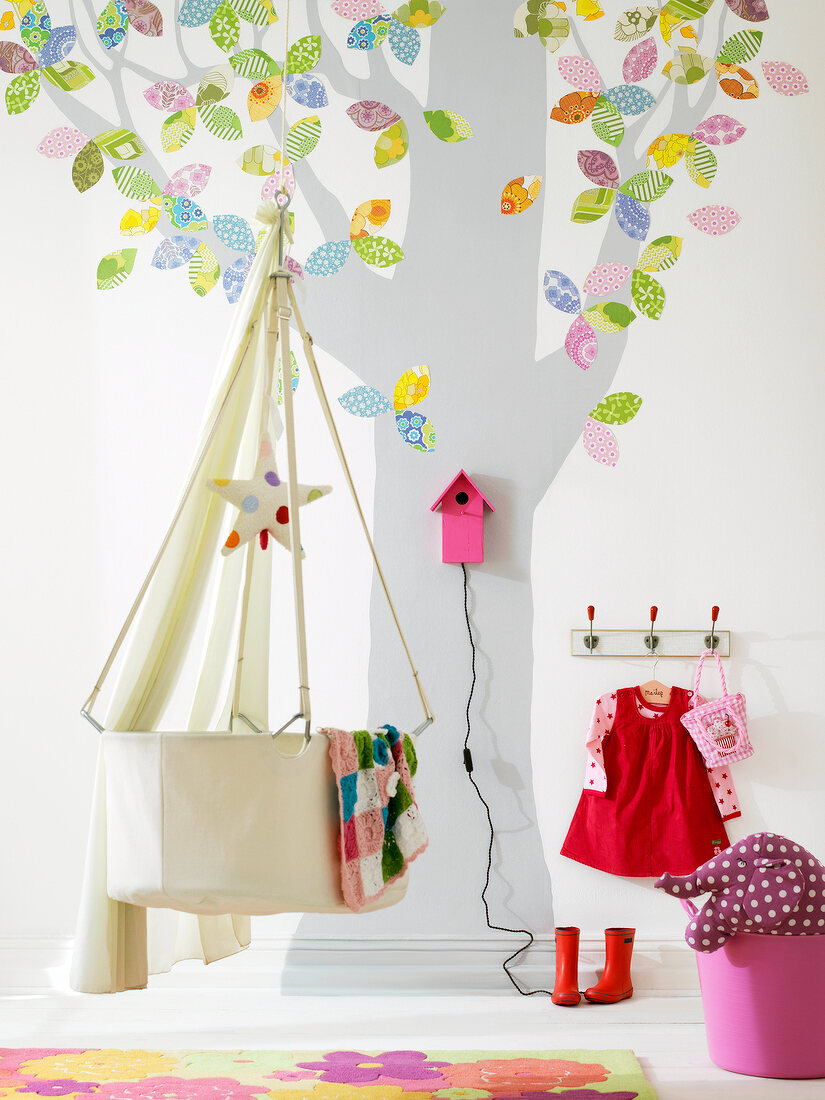 Baby room with white cradle and tree motif on wall
