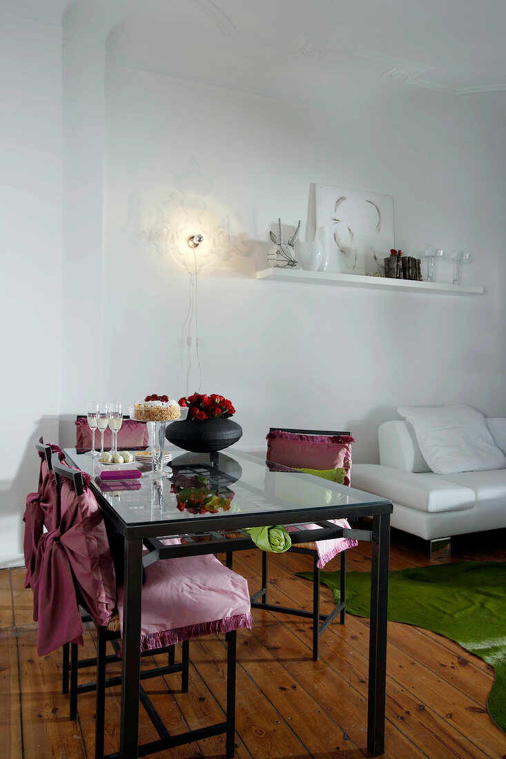 Table and chair with pink cover and champagne glasses on top with white sofa