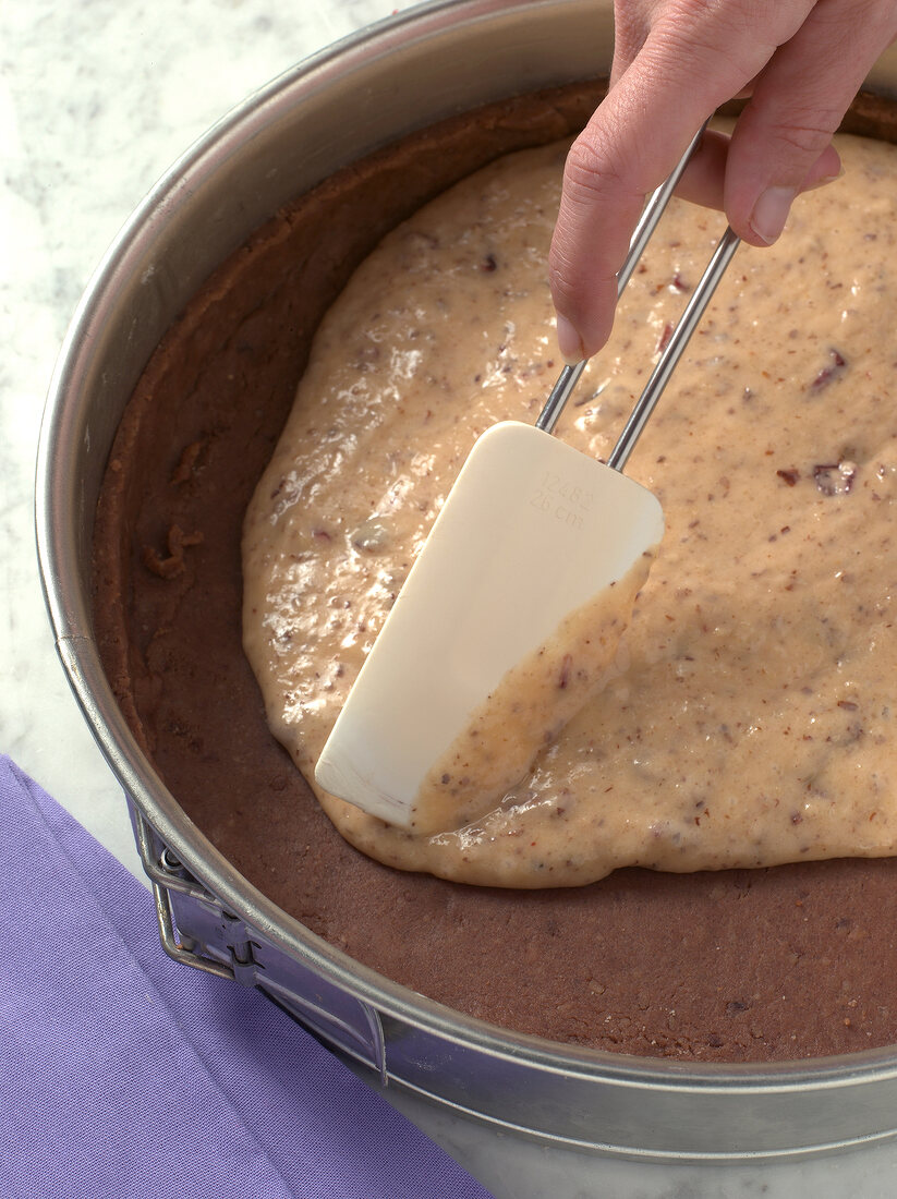 Close-up of hand spreading smooth mixture on baked bread, step 1