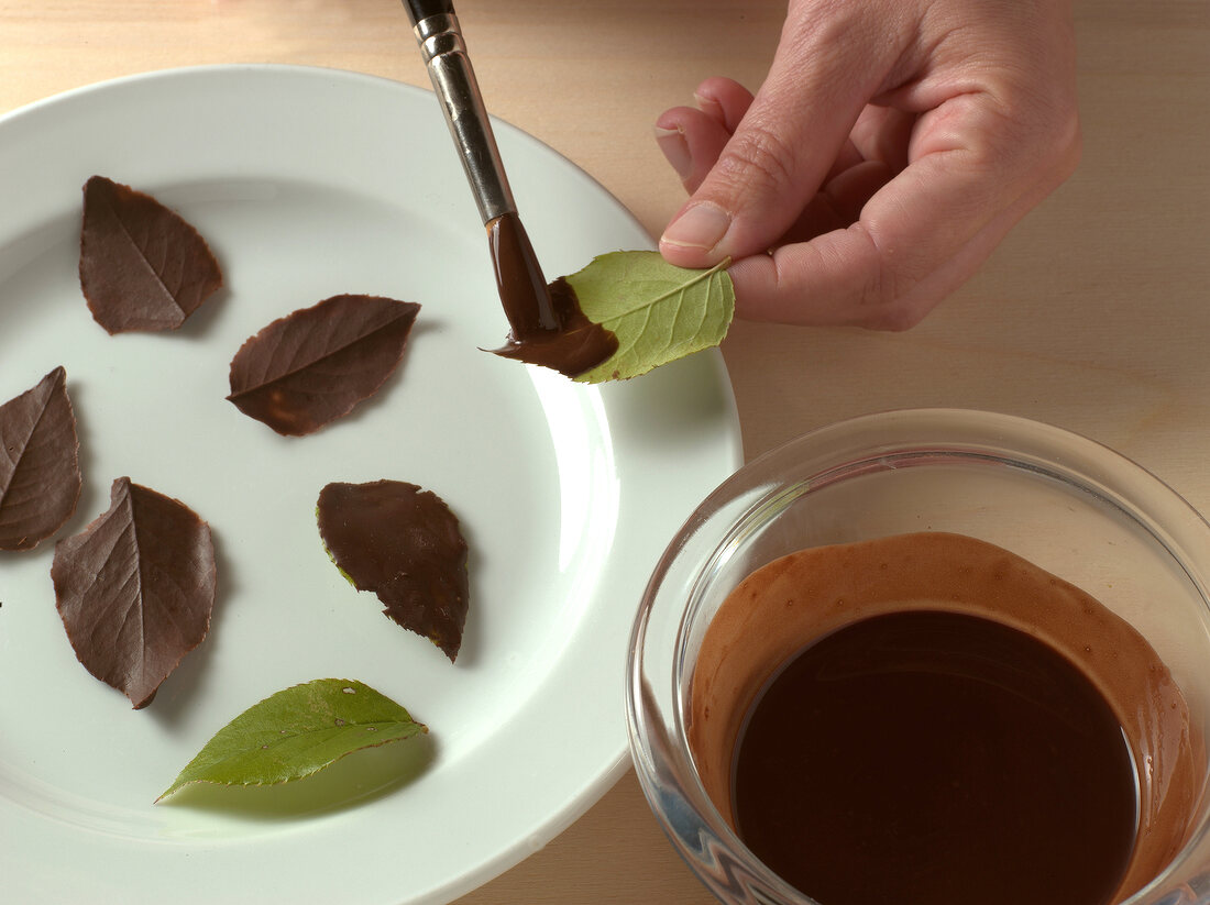 Close-up of hand making chocolate leaves for cake