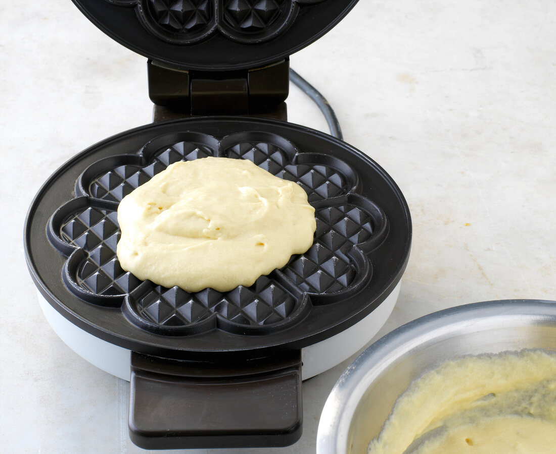Blob of dough placed on iron baker for preparation of waffles