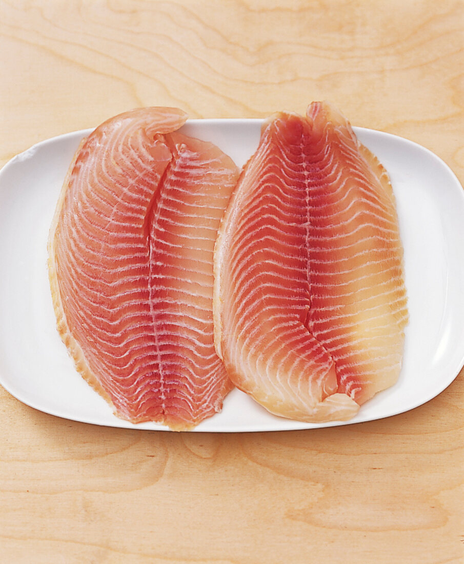 Two fillets of raw fish on plate