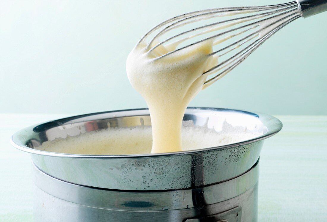 A bowl of waffle dough with a whisk