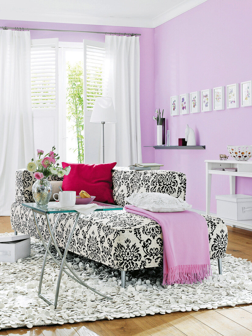Schwarz-weiß gemustertes Sofa, weiße Terrassentür, violette Wand