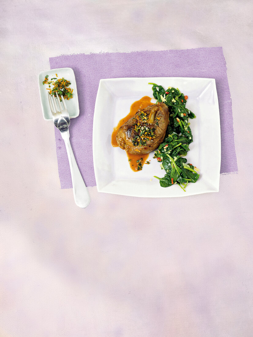 Braised lamb shank with lemon, ginger spinach and gremolata on square plate