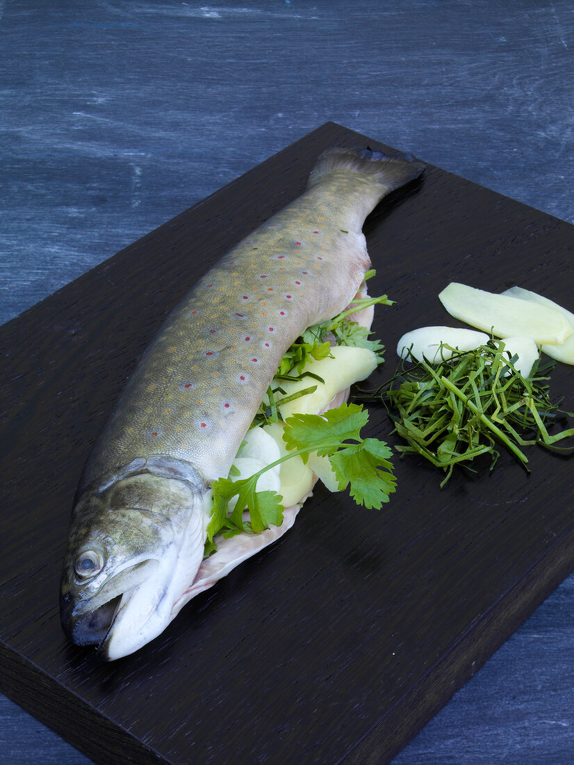 Fish filled with herbs and ginger on chopping board for preparation of barbecues, step 1