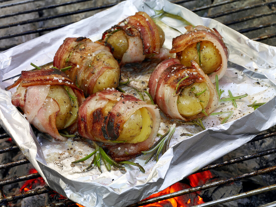 Bacon with potato filling and rosemary sprinkled on aluminium foil for grilling