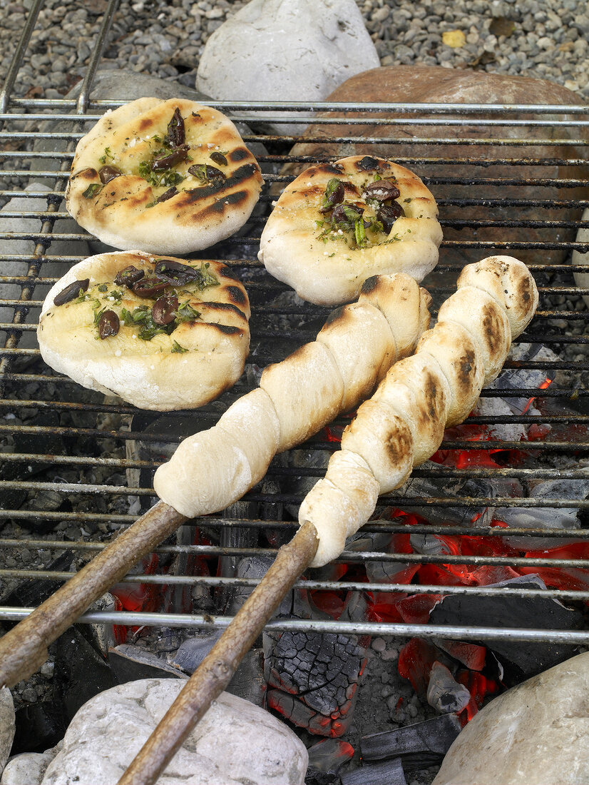 Stock breads and olive flatbread being grilled on barbecue