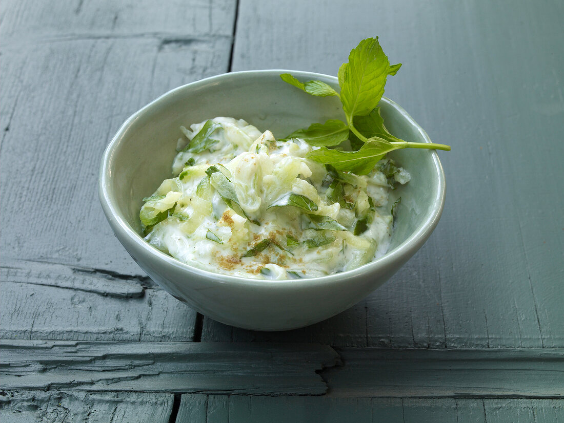 Bowl of tzatsiki with mint on wooden background