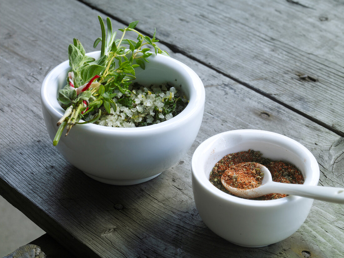 Two bowls of spicy salt and paprika with pepper seasoning on wooden table