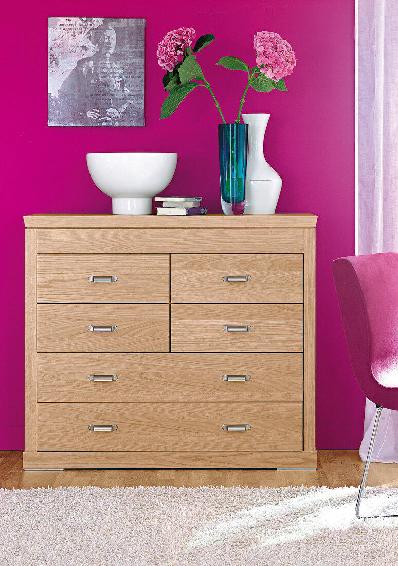 Drawer chest in light oak with vase against pink wall with picture