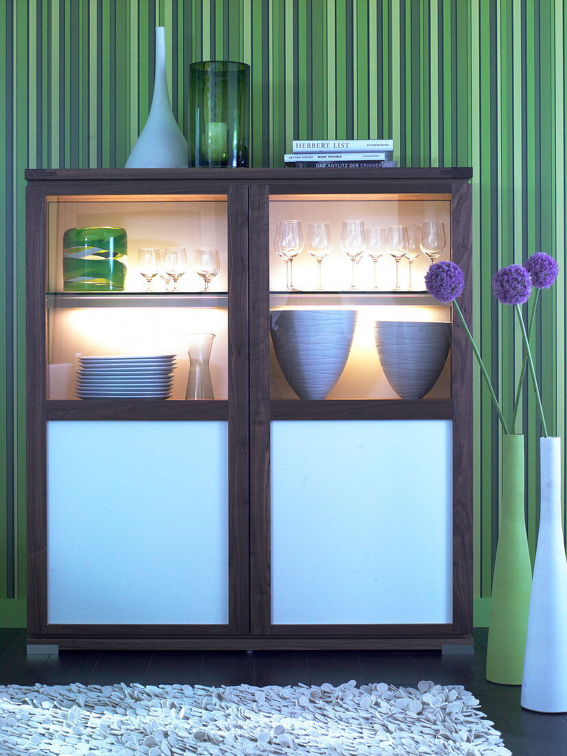 Illuminated walnut display case in light blue with bowls against green striped wall