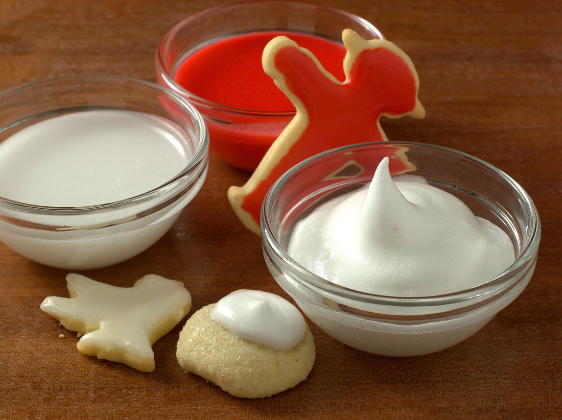 Red and white frosting in glass bowls for preparation of cookies