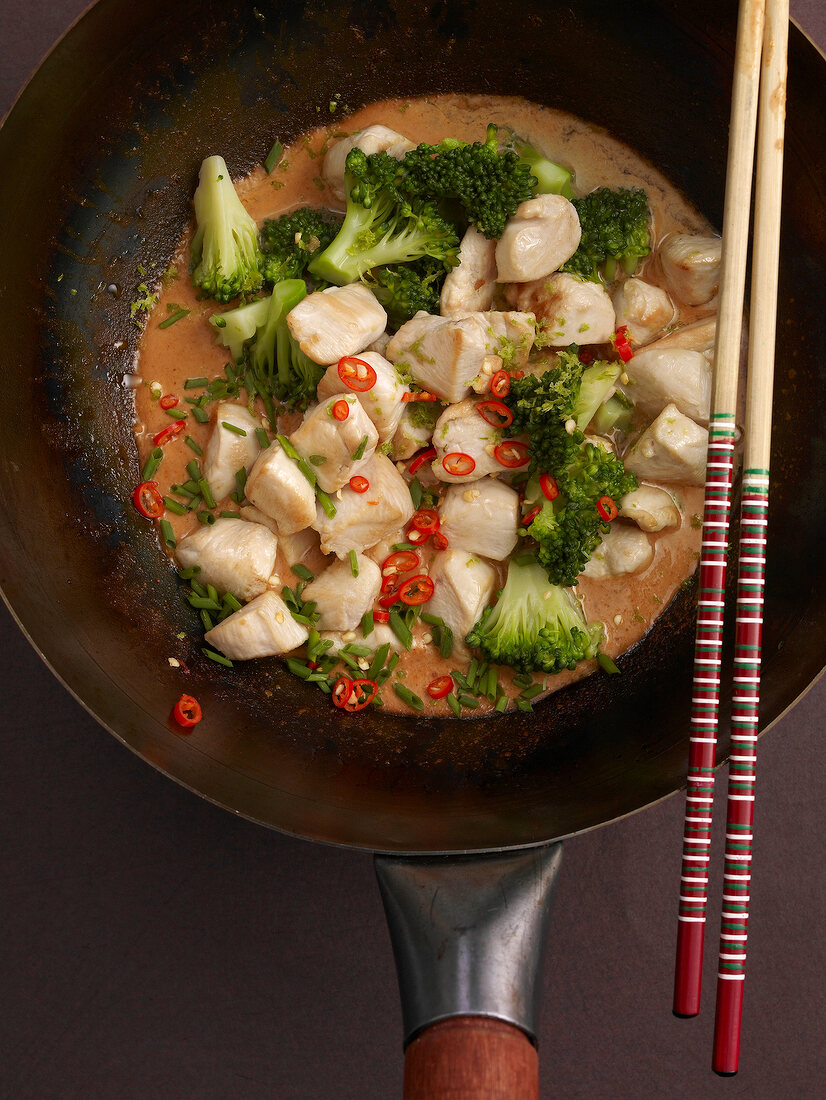 Chicken curry with broccoli, chilli and chives in frying pan